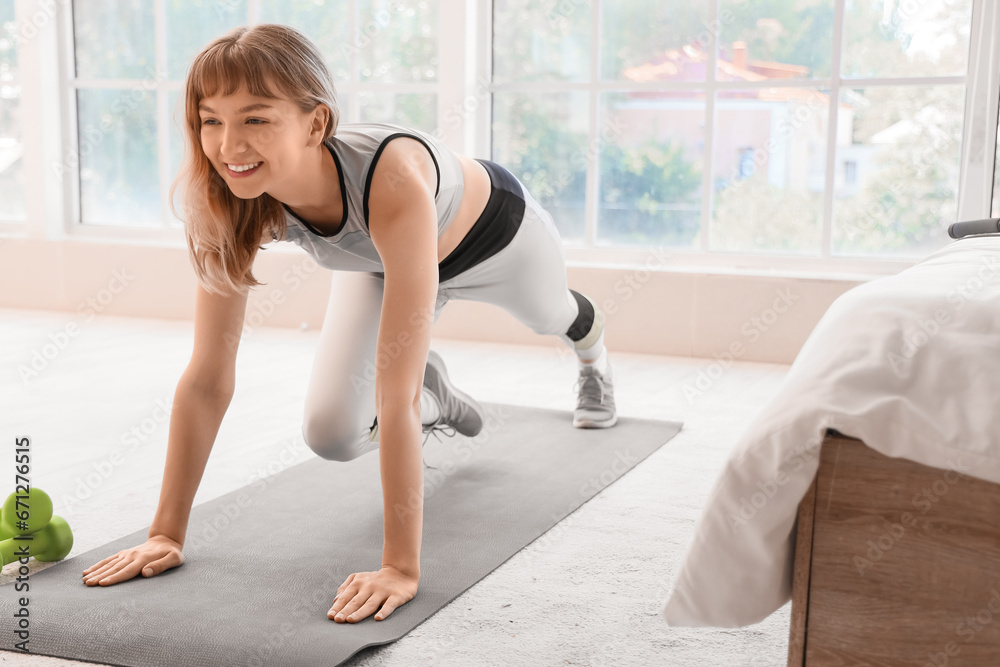 Beautiful young sporty woman training at home