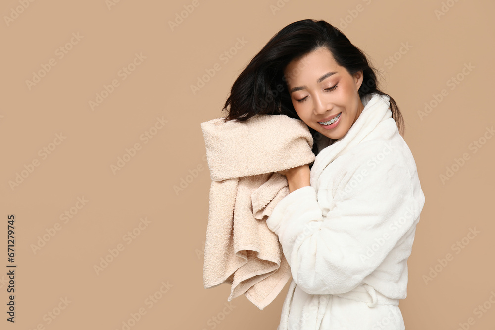 Young Asian woman wiping hair after shower on brown background