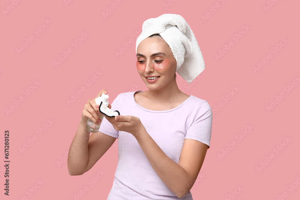 Young woman with reusable cotton pad and cleanser on pink background