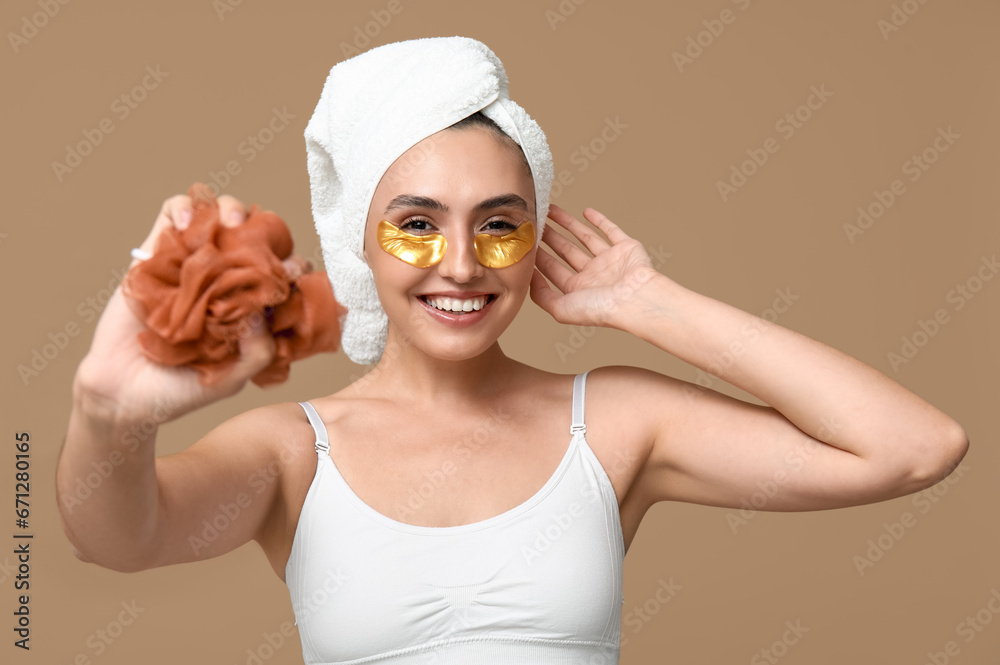 Young woman with loofah on brown background, closeup