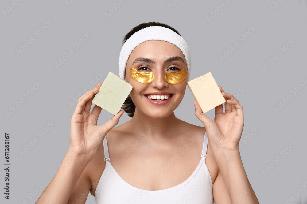 Young woman with soap bars on light background, closeup