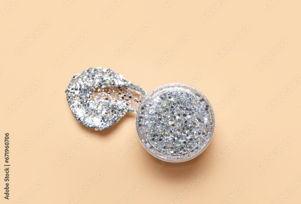 Jar of silver glitter with stroke on beige background