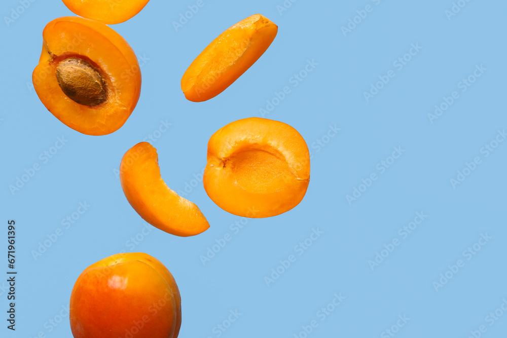 Flying fresh apricot with pieces on blue background