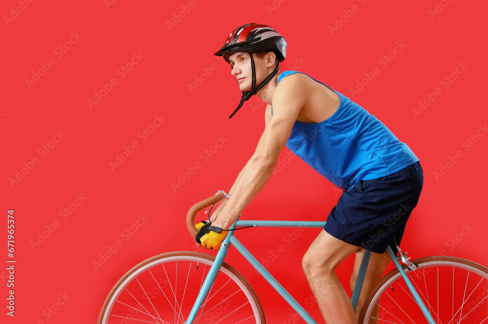 Young man riding bicycle on red background