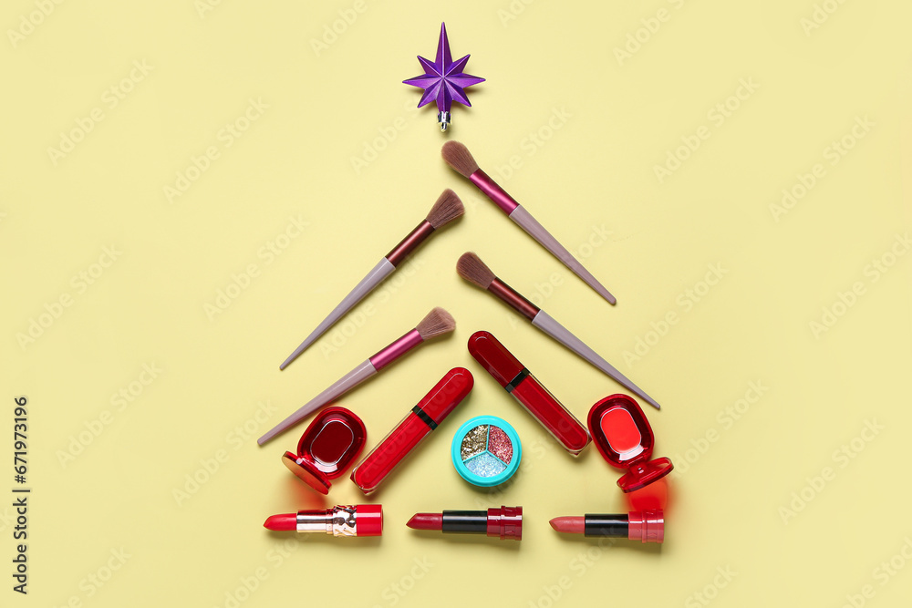 Christmas tree made of makeup products and decor on yellow background