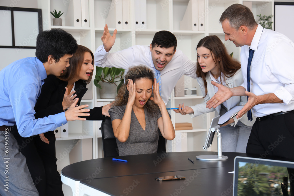 Mature businesswoman suffering from noisy colleagues in office