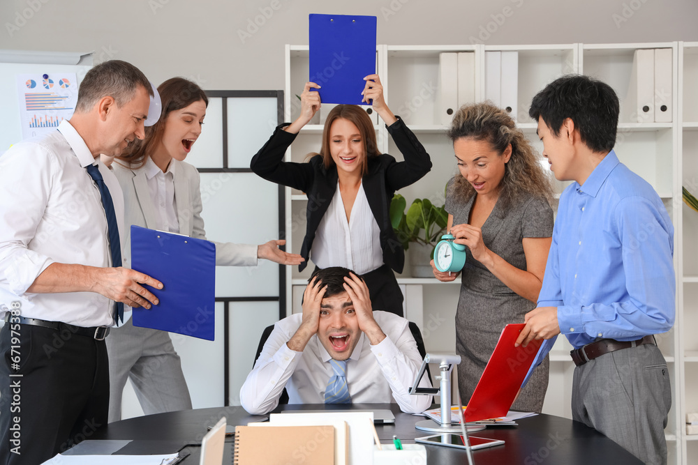 Mature businessman suffering from noisy colleagues in office