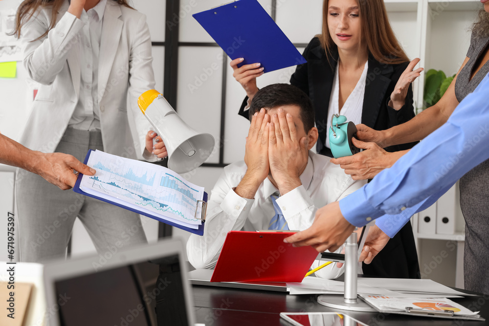 Mature businessman suffering from noisy colleagues in office