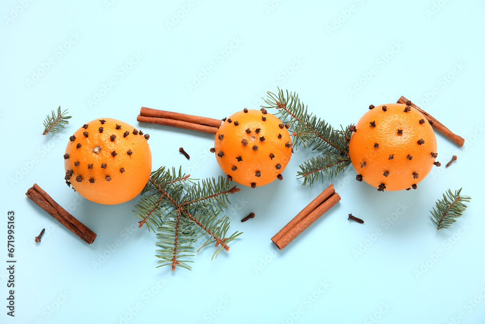 Pomander balls with Christmas tree branches and cinnamon on blue background