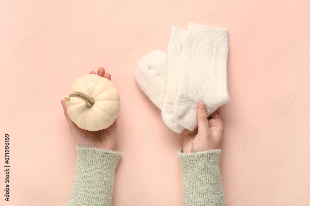 Woman with pumpkin and warm socks on beige background