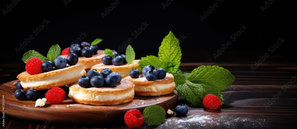 A delicious and healthy breakfast consisting of pancakes made with cottage cheese accompanied by cheesecakes topped with fresh blueberries strawberries honey and mint leaves These delightful