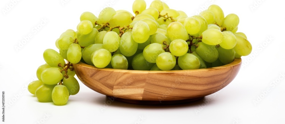 Arrangements of ripe green grapes on a wooden tray against a white backdrop