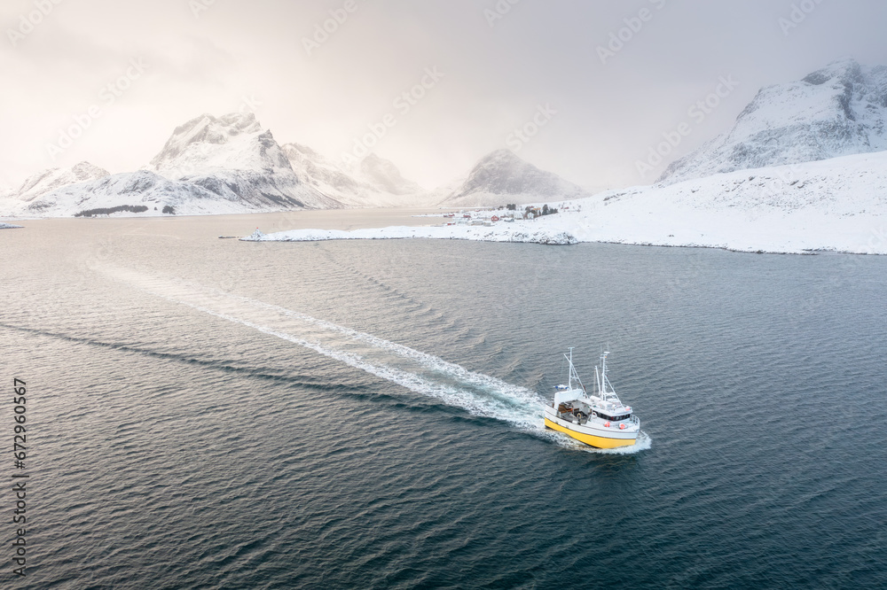 Fishing boat in the fjord. Aerial view of Lofoten Islands, Norway. Industrial fishing. View from a drone. Aerial landscape. Mountains and water. Image of Norway