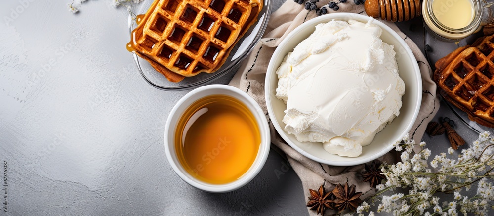 On a light kitchen countertop a variety of ingredients including cane sugar and butter are arranged in a top down view to create homemade chocolate waffles The waffles are placed on a gray b