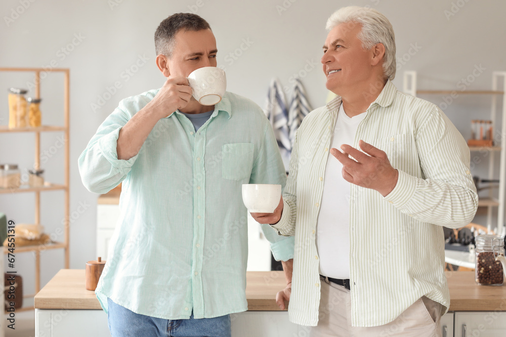 Mature brothers drinking tea in kitchen