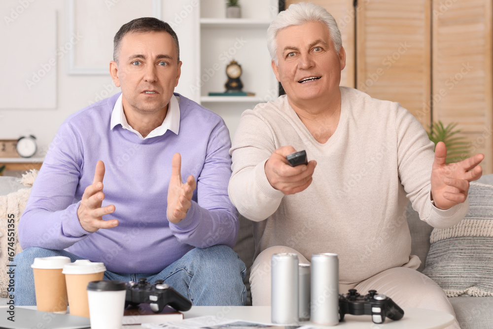 Mature brothers watching TV at home