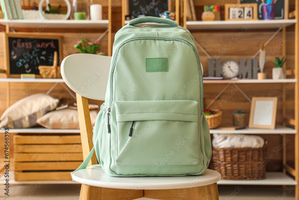 Stylish school backpack on chair in room