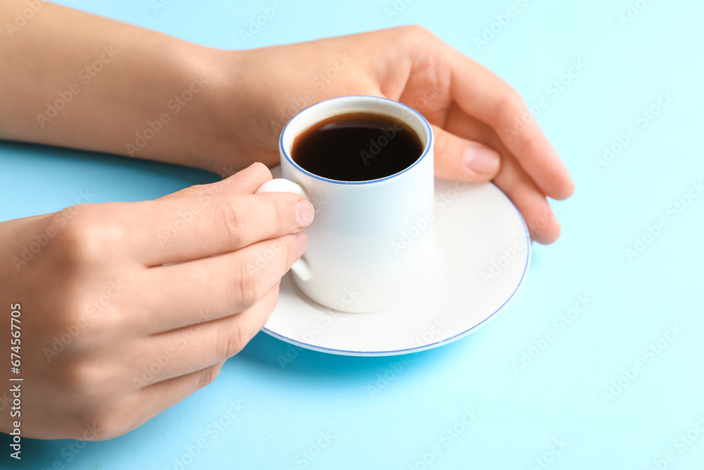 Woman holding cup of hot coffee on blue background