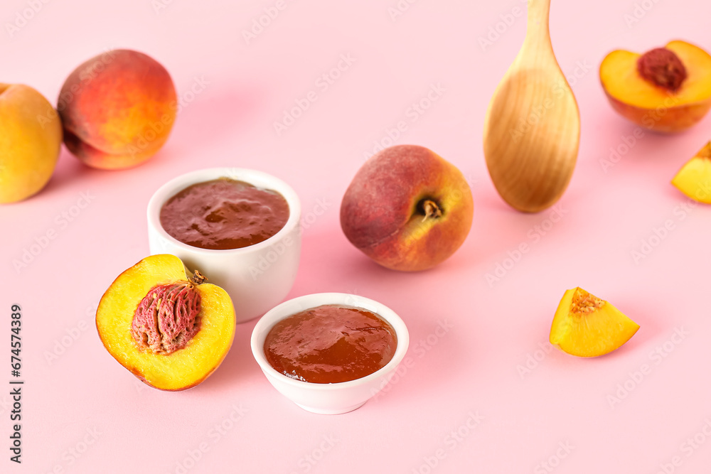 Bowls with sweet peach jam and fresh fruits on pink background