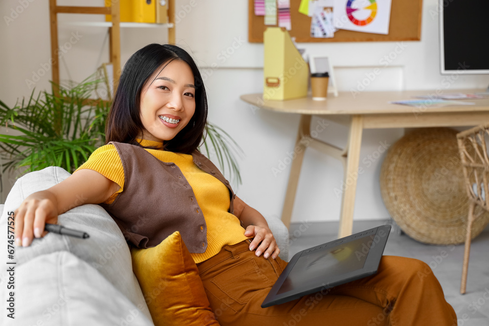 Asian interior designer working with tablet on sofa in office