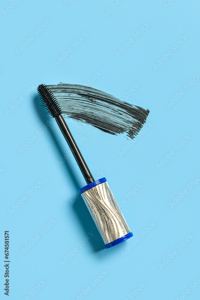 Black mascara brush with sample on blue background