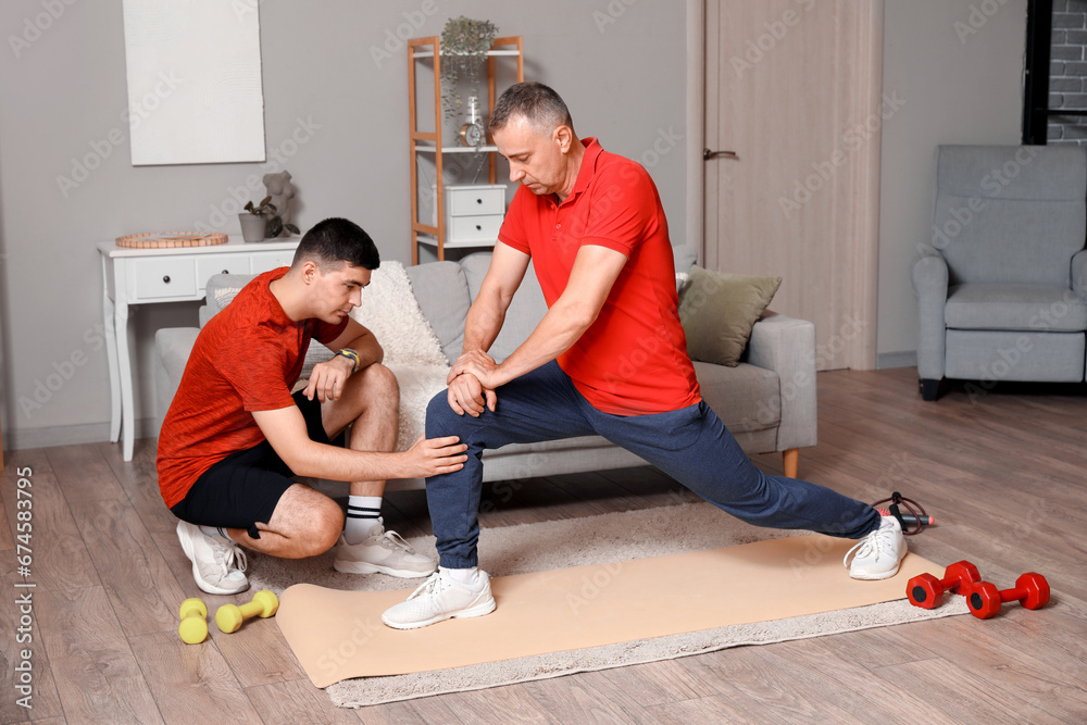 Mature man training with rehabilitation therapist at home