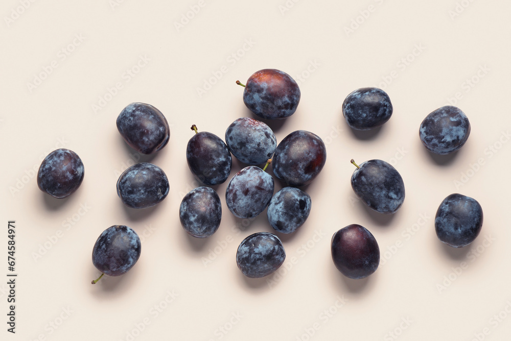 Many fresh plums on beige background