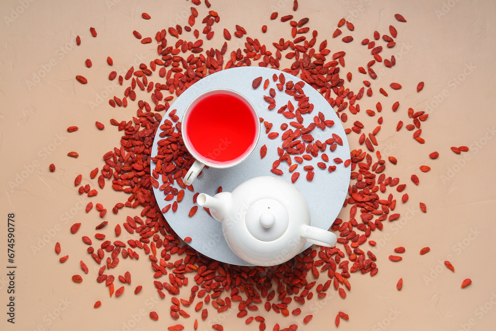 Red dried goji berries and cup of hot tea on beige background