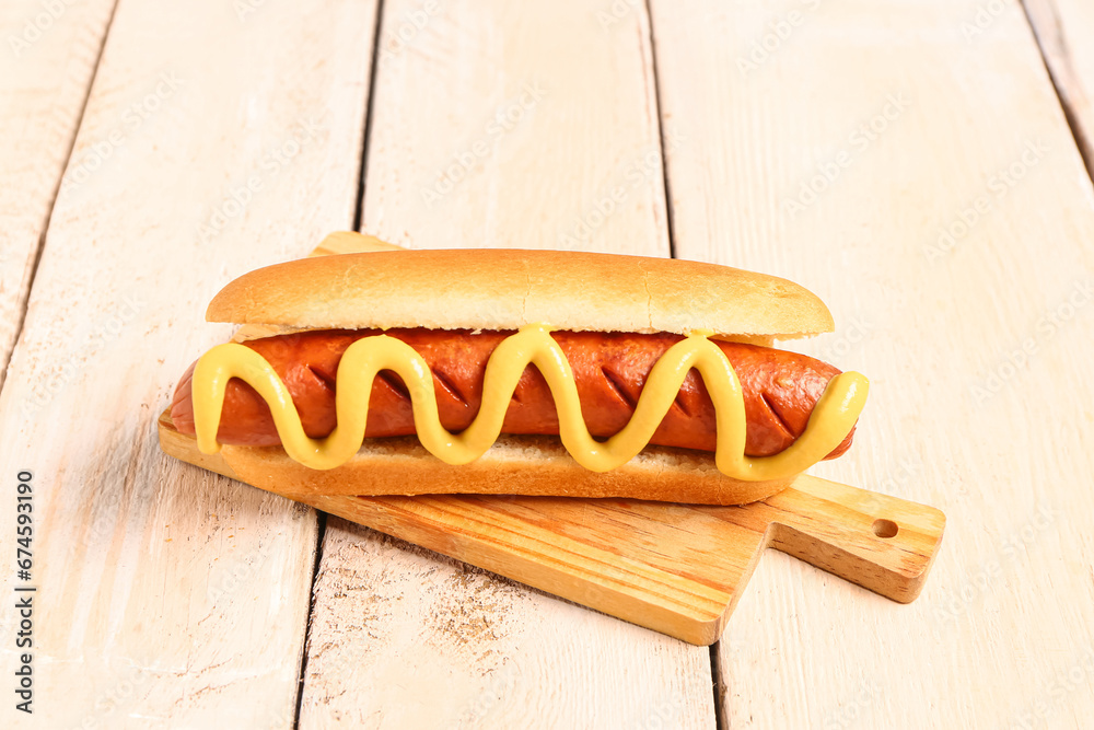 Board with tasty hot dog on white wooden background