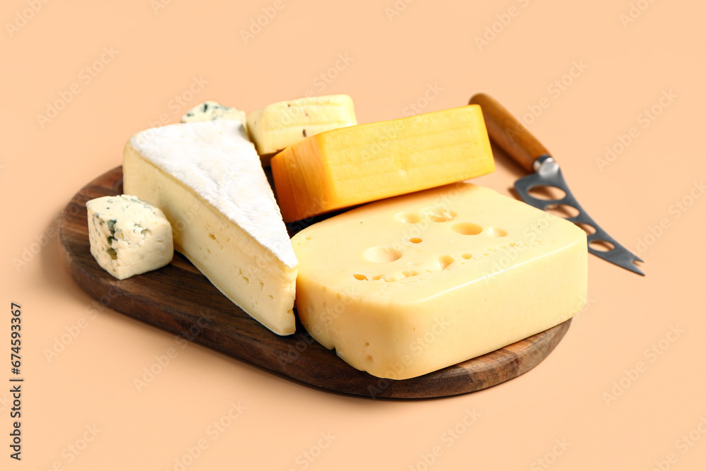 Wooden board with tasty cheese on beige background