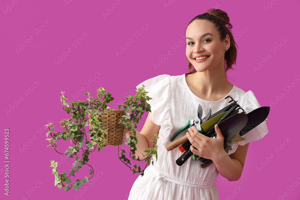 Young woman with gardening tools and plant on purple background