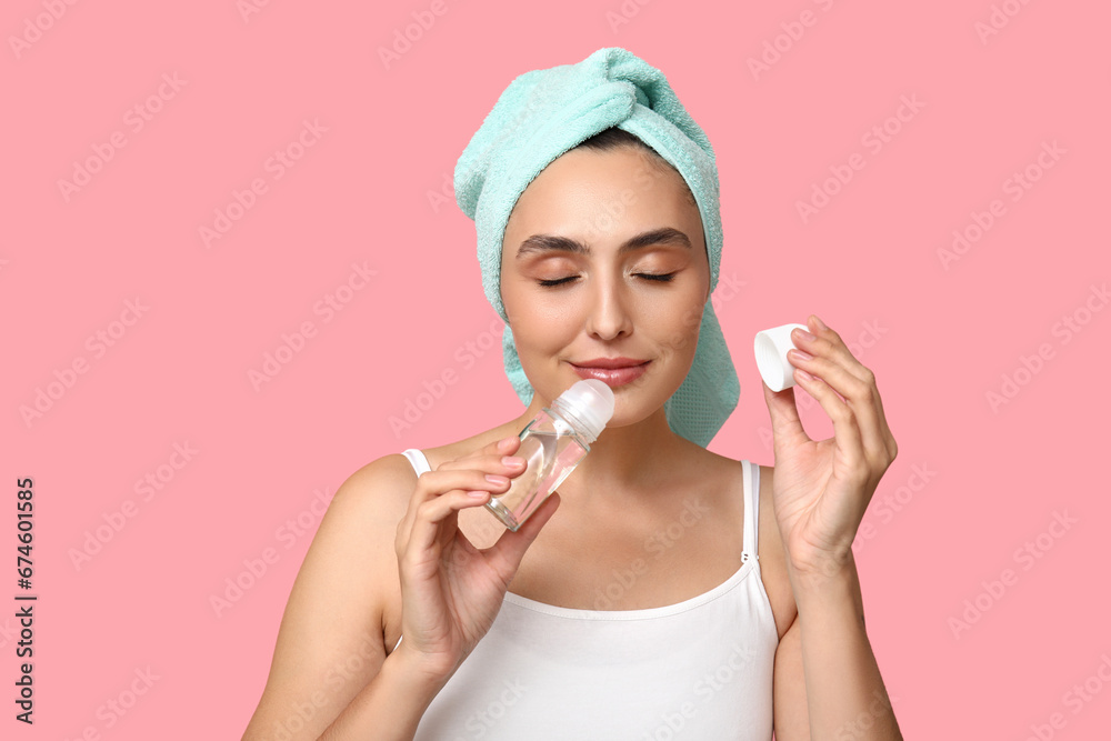 Young woman with roll-on deodorant on pink background, closeup