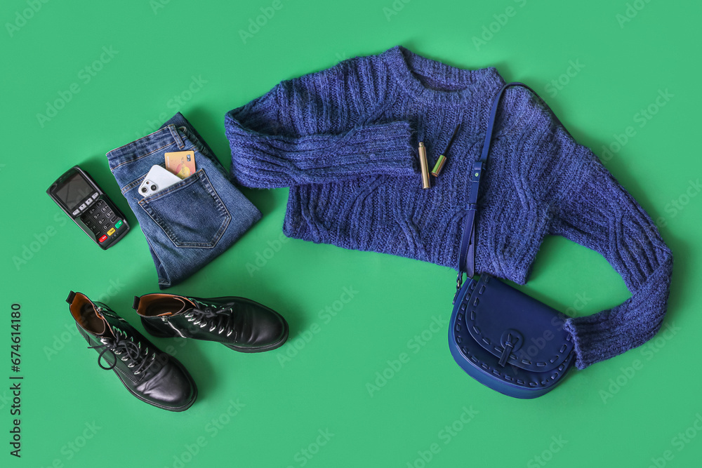 Winter clothes with accessories, payment terminal and credit card on green background