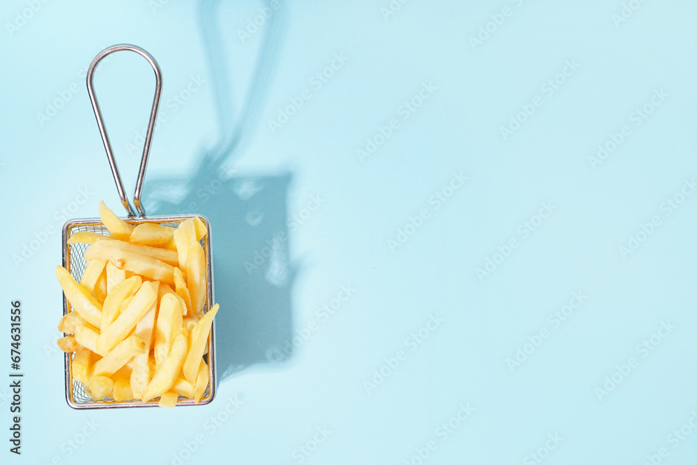 French fries in metal basket on blue background