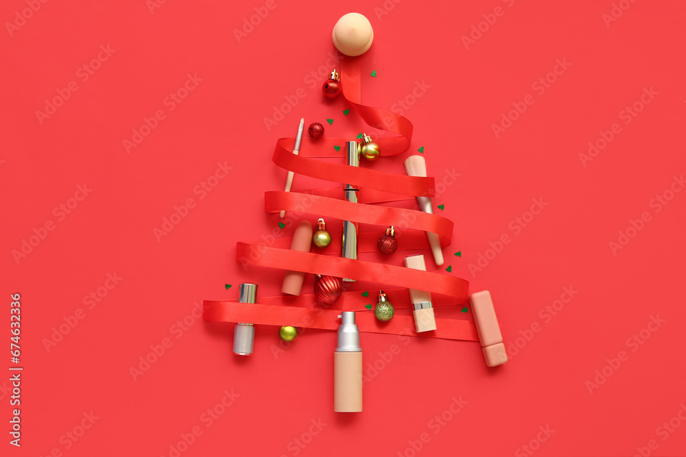 Christmas tree made of different makeup products and decor on red background