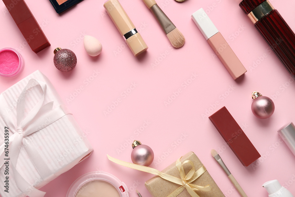 Frame made of different makeup products and Christmas balls on pink background