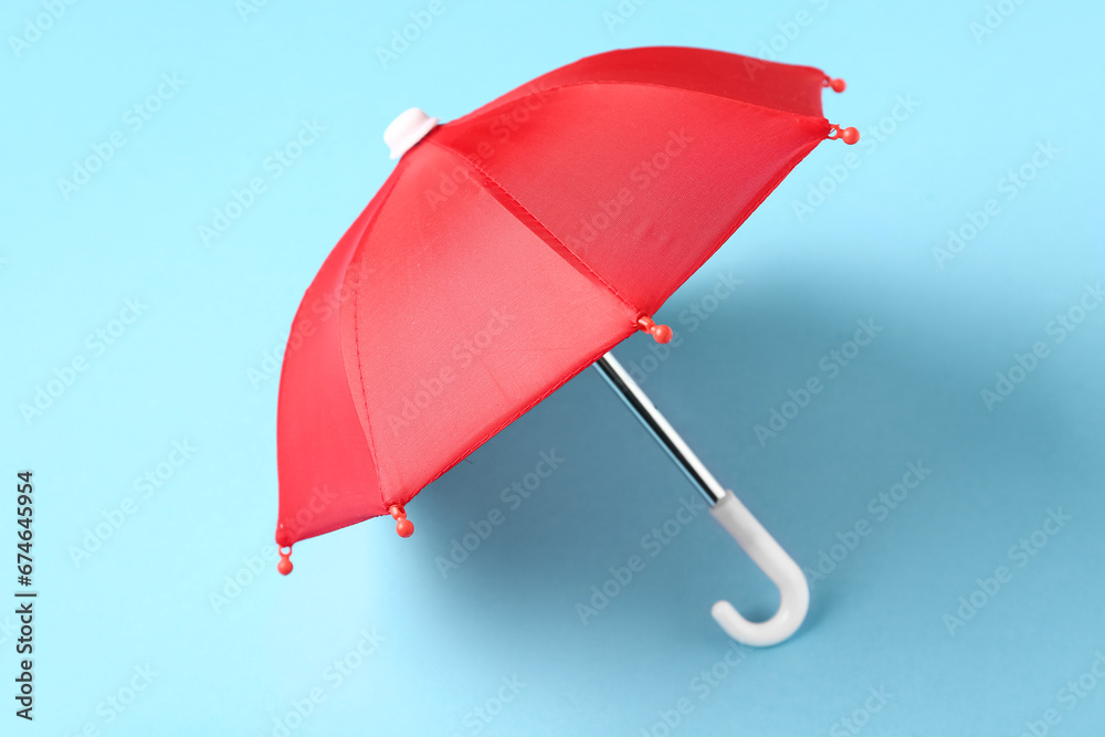 Mini red umbrella on blue background