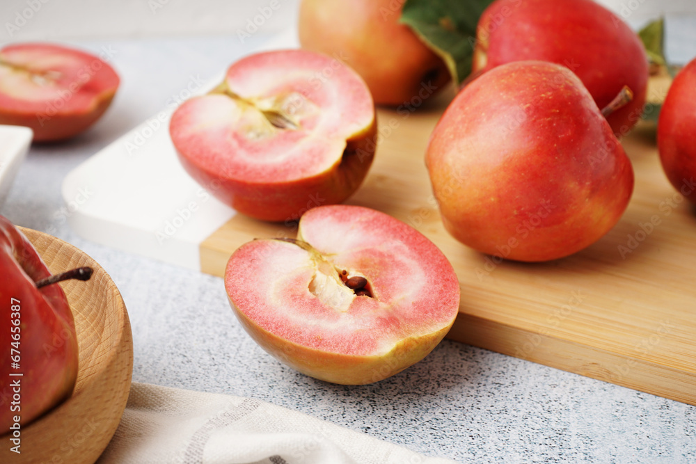 Board with sweet pink apples on white background