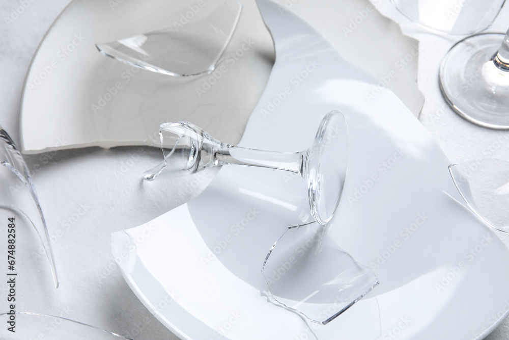 Closeup view of broken glasses and dishes on light background