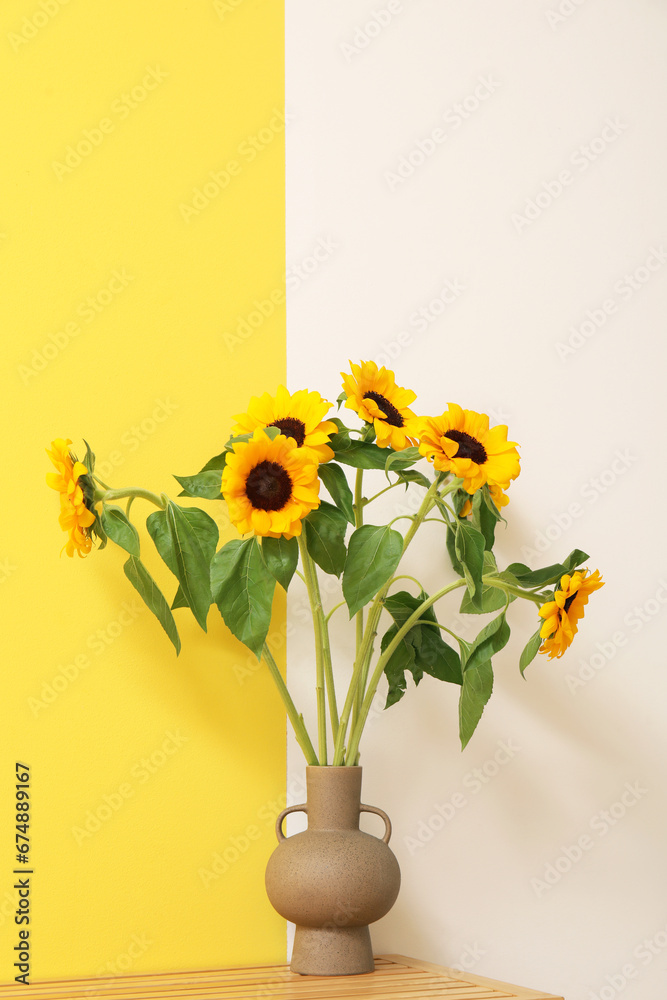 Vase with sunflowers on shelf near yellow and white wall