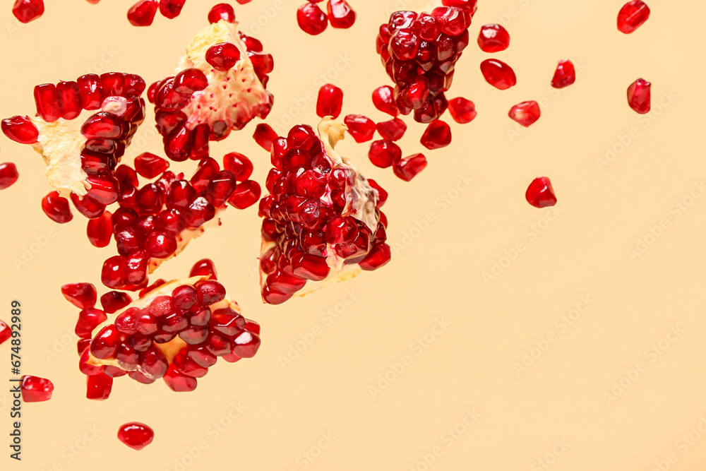 Flying fresh pomegranates with seeds on yellow background