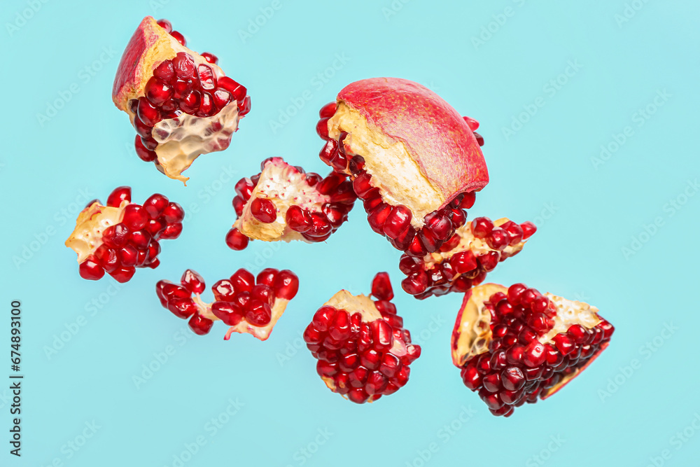 Flying fresh pomegranates on blue background