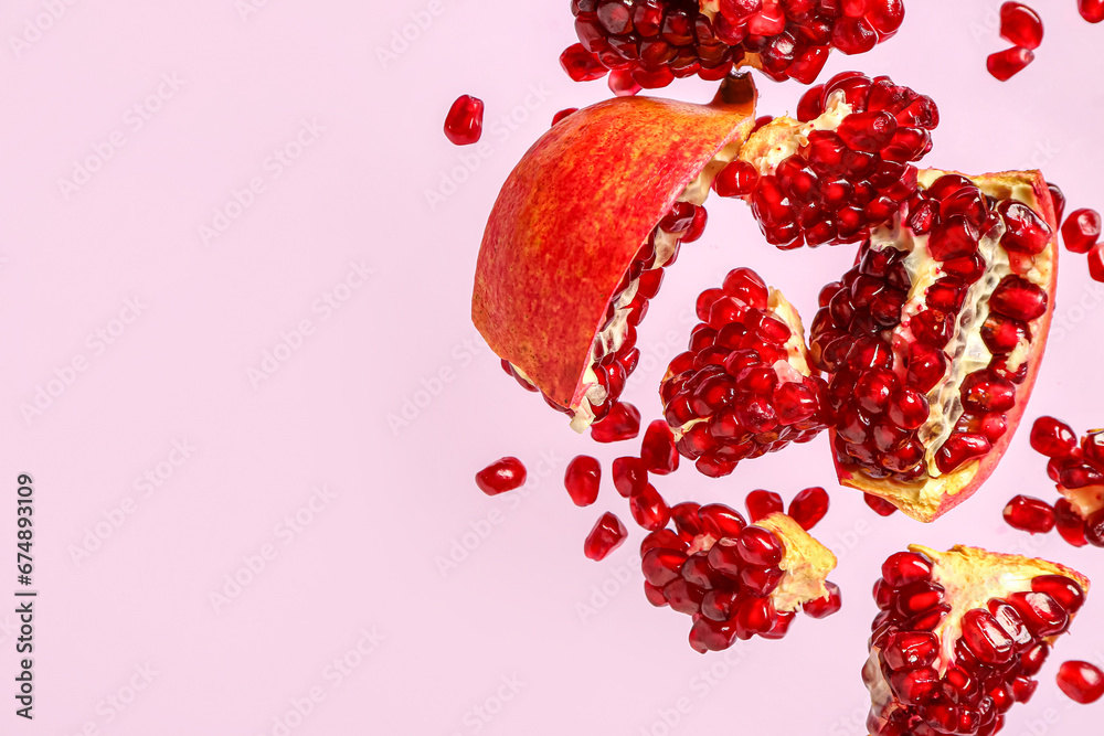 Flying fresh pomegranates with seeds on lilac background