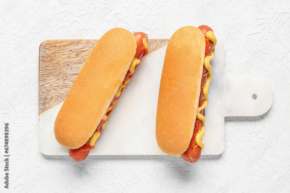 Board with tasty hot dogs on white background