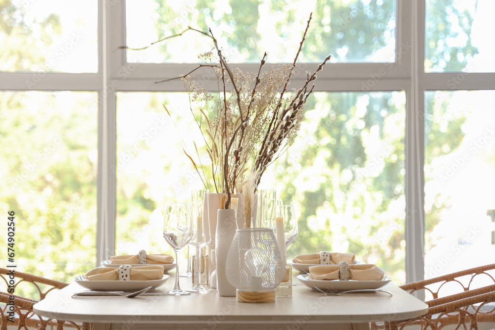 Elegant table setting with candles, dried flowers in vases and glasses