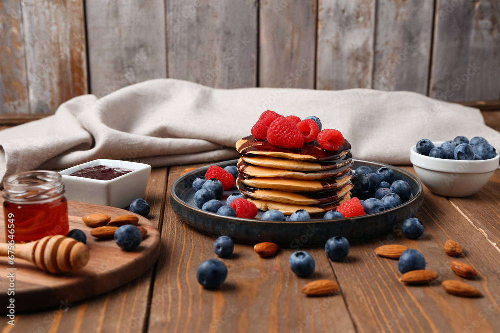 Plate with sweet pancakes, nuts and berries on wooden table