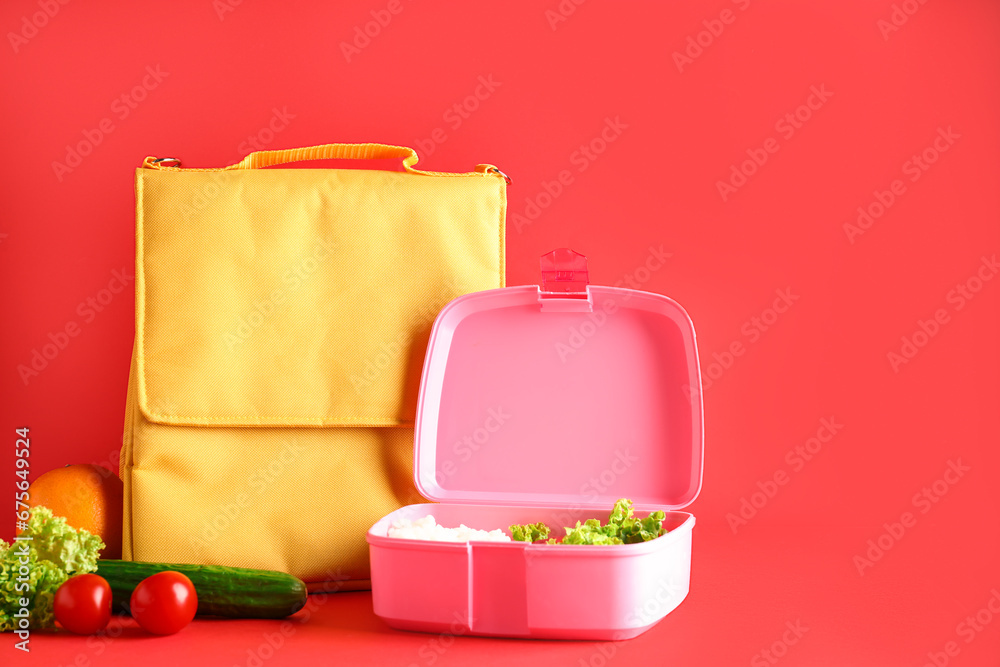 Bag and lunchbox with tasty food on red background