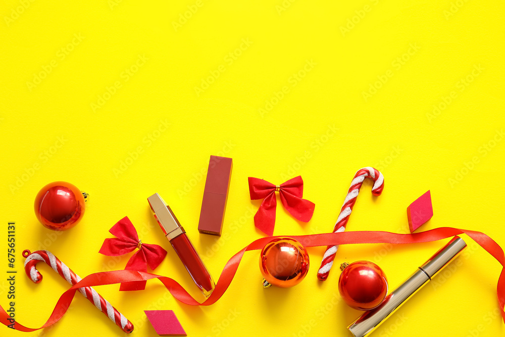 Makeup products and red Christmas decorations on yellow background