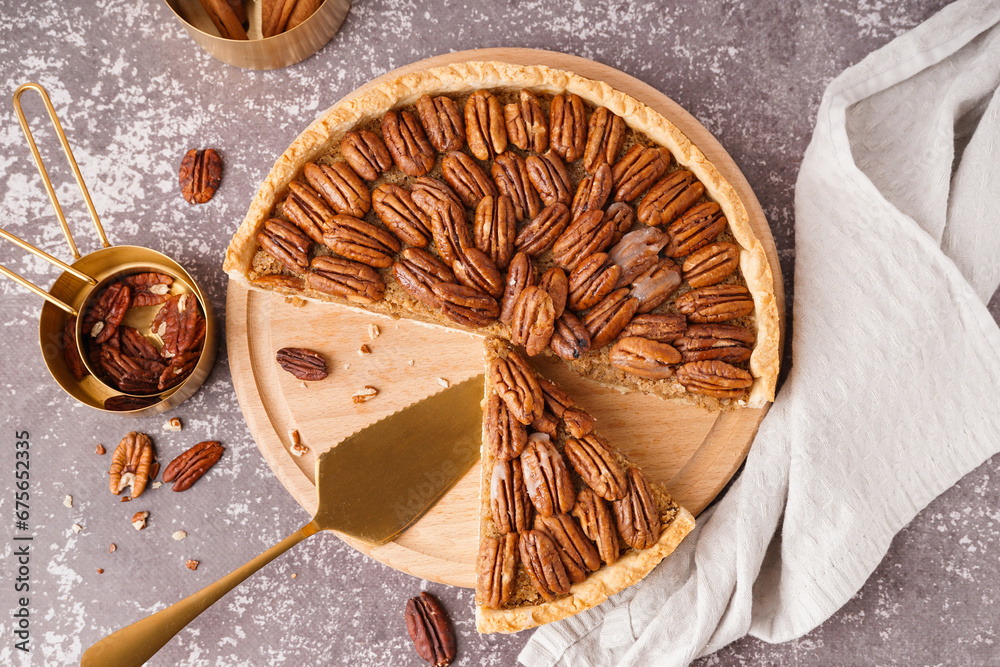 Wooden board with tasty pecan pie on grey background