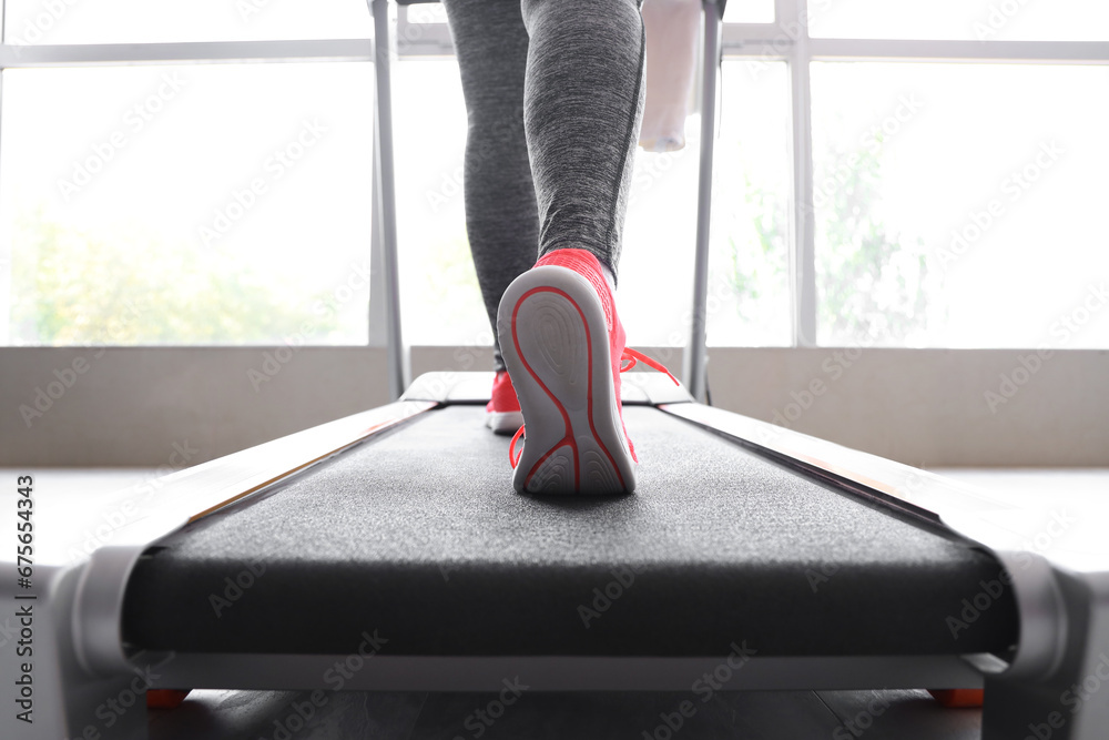 Woman running on treadmill in gym, closeup of legs